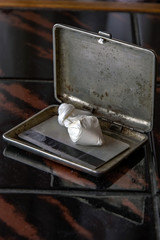 dose of cocaine in a plastic bag and a card inside an open cigarette case, on a dark background