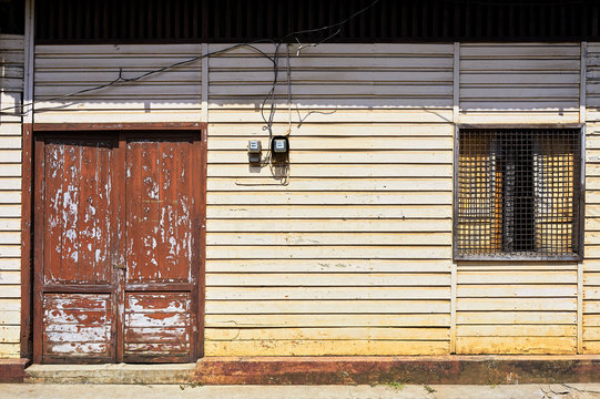 Close-up view of a front facade of a typical wooden house with an old door and a window with metal grills for protection in Cuyo, Palawan, Philippines