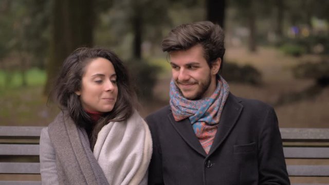 First date. shy, awkward Young attractive lovers sitting on bench in the park