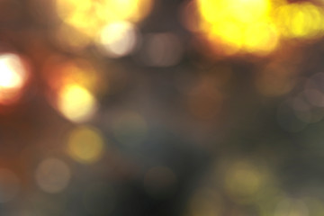 Abstract blurred bokeh background, glowing gold, soft brown, red, and earth tones. Lights out of focus festive warm cozy atmosphere blurry wallpaper. 