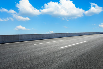 Fototapeta premium Empty asphalt road ground and blue sky with white clouds scene