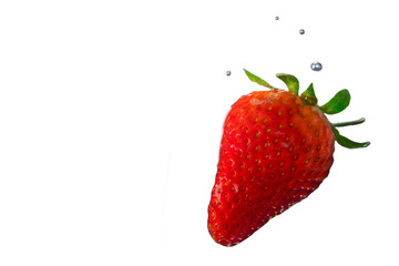 Strawberry dipped in water with bubbles on white background