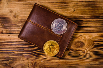 Brown leather wallet and bitcoins on the wooden background. Top view