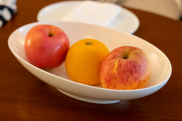 Fruit bowl on a wooden table with apples and oranges