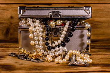 Aluminium case full of different jewelry on wooden table