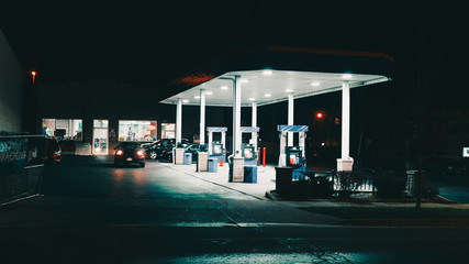 bright gas station on a very dark night in an urban city with few cars