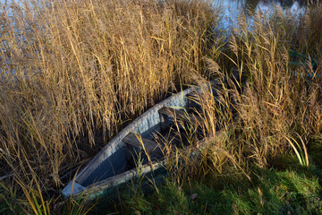 Lonely old wooden fishing boat on autumn lake coast