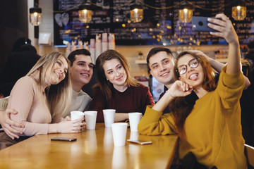 Five young handsome students sitting in a cafe.