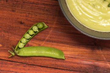 sopa de arvejas con pan en mesa de madera rustica