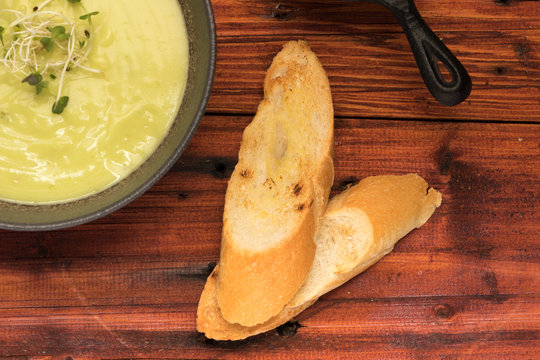sopa de arvejas con pan en mesa de madera rustica