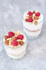 Two glasses of a greek yogurt granola with raspberries, oatmeal flakes and nuts, top view. Healthy nutrition
