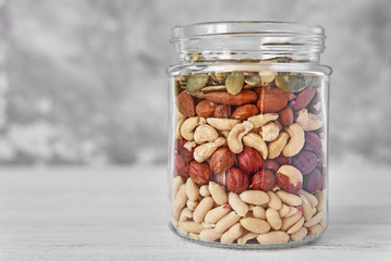 Layers of different types of nuts and seeds in a glass jar close up