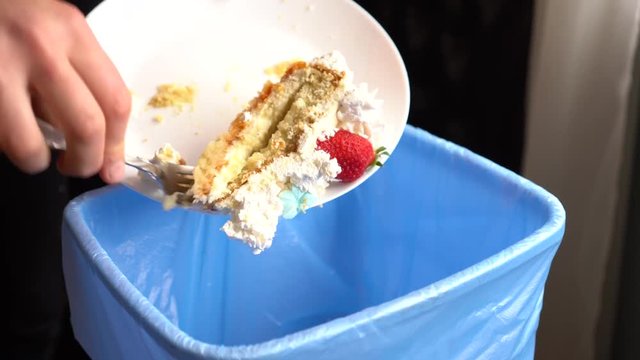 Young woman throws in the kitchen compost bin uneaten cake. Food waste problem. Healthy diet