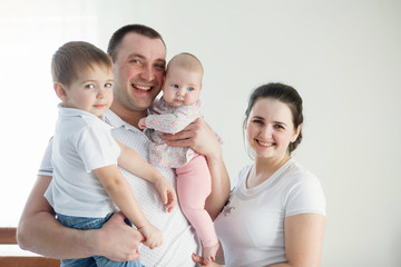 Family of four standing on white background.