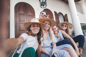 Group of happy joyful young stylish girls travel together, in hats against the background of a...