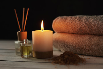 Towels, candle and massage oil on white table