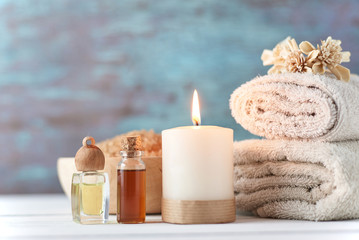 Towels, candle and massage oil on white table