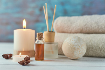 Towels, candle and massage oil on white table