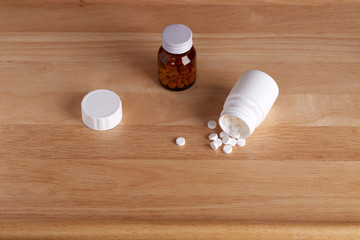 Glass and plastic bottles for medications. Scattered round white tablets. Horizontal shot.