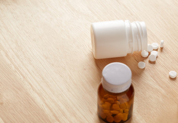 Glass and white plastic bottles for medications. Scattered round white tablets. Horizontal shot.