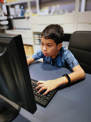 Asian Boy Using Computer Typing and Looking at Monitor