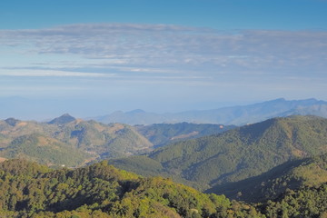 Fototapeta na wymiar Mountain view morning on top of Doi Ang Khang above many hills and green forest cover with soft mist and blue sky background, Doi Angkhang, Chiang Mai, northern of Thailand.