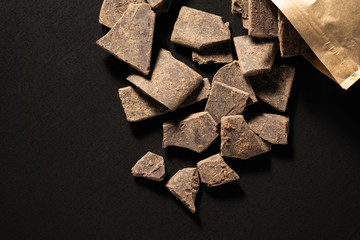 Natural chocolate without sugar from grated cocoa beans, in eco packaging on a dark background