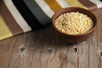 couscous croup in a clay bowl on a wooden background