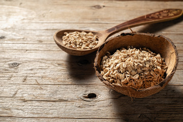 raw syrodavlennaya oatmeal in a coconut bowl on a wooden background, top view, place under the text