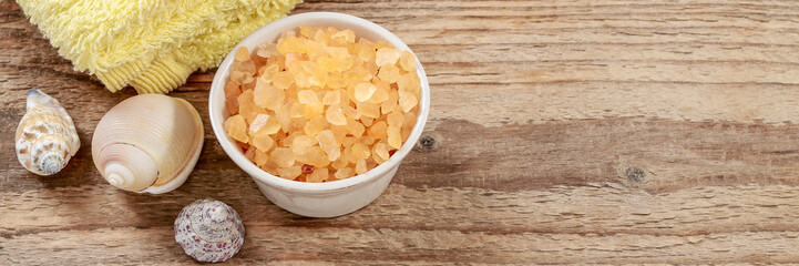 Soft towels, sea salt and shells on wooden background. Spa concept
