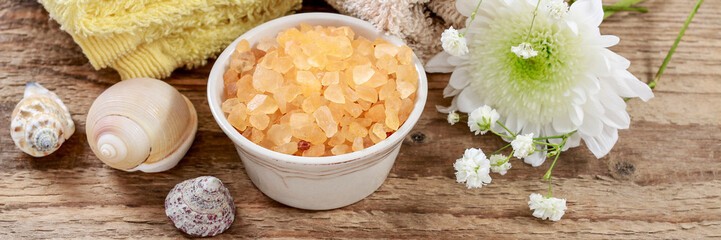 Soft towels, sea salt and shells on wooden background. Spa concept
