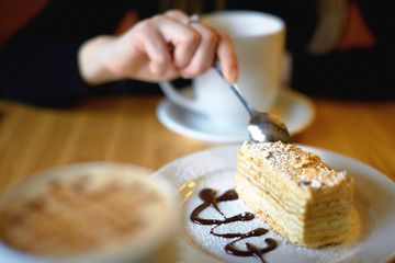a piece of napoleon cake on a white plate with a cup of coffee