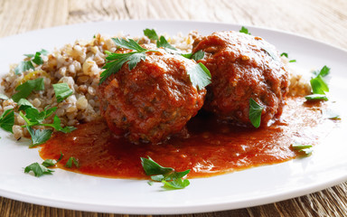 beef cutlets in tomato sauce garnished with  buckwheat porridge with fried onion and decorated with parsley