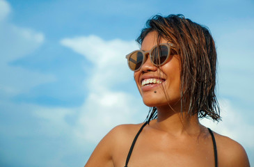 head and shoulders lifestyle portrait of young beautiful and sexy Asian girl in bikini and sunglasses enjoying holidays at tropical beach posing cool smiling happy at the sea