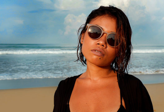 head and shoulders lifestyle portrait of young beautiful and sexy Asian girl in bikini and sunglasses enjoying holidays at tropical beach posing cool and confident at the sea