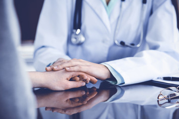 Doctor and  female patient sitting at the desk and talking  in clinic near window. Medicine and health care concept. Green is main color