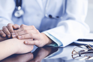 Doctor and  female patient sitting at the desk and talking  in clinic near window. Medicine and...