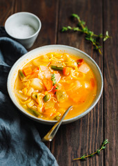 Spring vegetable soup with chicken stock for one person on wooden table. Rustic style, close-up view.