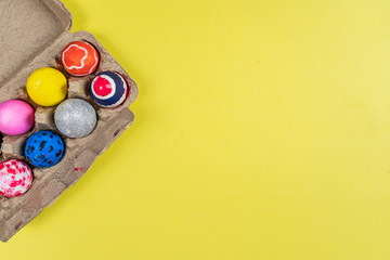 colored easter eggs on yellow background in flat lay with copy space