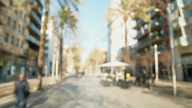 First-person POV handheld shot: walking on a public street at day, everything is blurry and defocused.