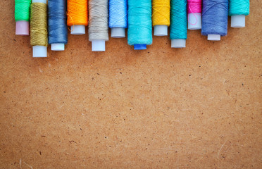 Multicolor sewing threads on a roll for sewing on a wooden background. With copy space