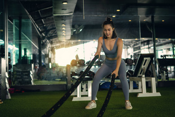 Fototapeta na wymiar Woman with battle rope battle ropes exercise in the fitness gym. exercises concept. healthy concept heavy exercise in gym fitness.
