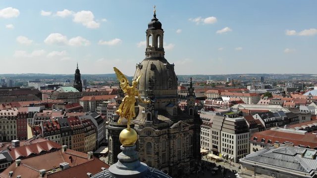 Drone footage of golden Fama figure statue on top of Zitronenpresse with Frauenkirche in background in Dresden, Germany