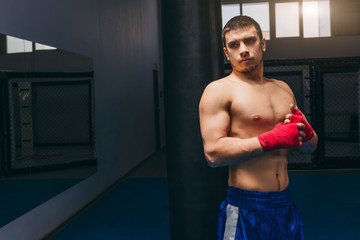 Portrait of young male boxer with strong naked torso, engaging in sport boxing activity to increase...