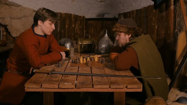 Two men in russian ethnic suit playing medieval popular strategy board game - tafl. Folk, competition and traditional concept