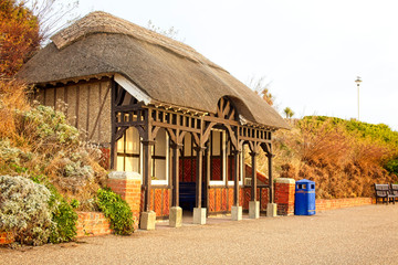 One of the thatched shelters along Eastbourne Promenade, East Sussex, England, UK. - obrazy, fototapety, plakaty