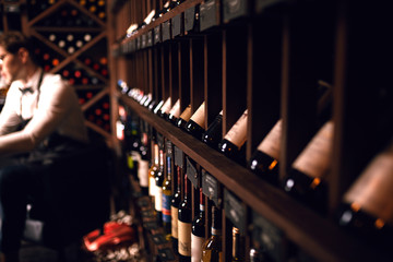 Portrait of sommelier perfectly skilled in wine etiquette, selecting wines, exquisite service for presenting wine to the customer putting down some notes in his note pad in restaurant.
