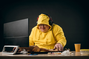 Funny guy in yellow hoody getting pleasure from online games. close up photo. isolated black background.studio shot. computer hacker making up a new programme.crime concept - obrazy, fototapety, plakaty