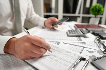 Businessman working at office and calculating finance, reads and writes reports. Business financial accounting concept.