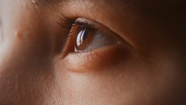 Close-up of beautiful girl's eye. Brown eyes, women, close-up shot. The girl looks up, blinks, side view in profile. Slow motion, warm light. 4K